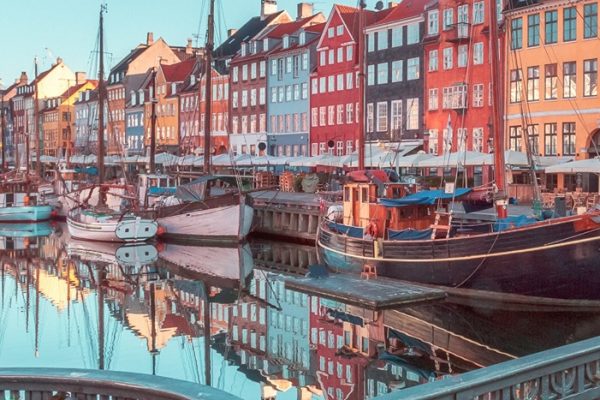 A bright and reflective shot of the Copenhagen harbour with cute homes in the background during womens travel network's Scandinavia tour for women